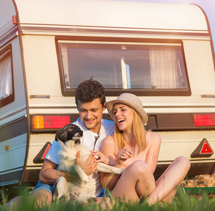 A couple outside their caravan with their dog watching the sunset protected by Moving Intelligence’s specially designed GPS tracking devices with insurance accreditation.