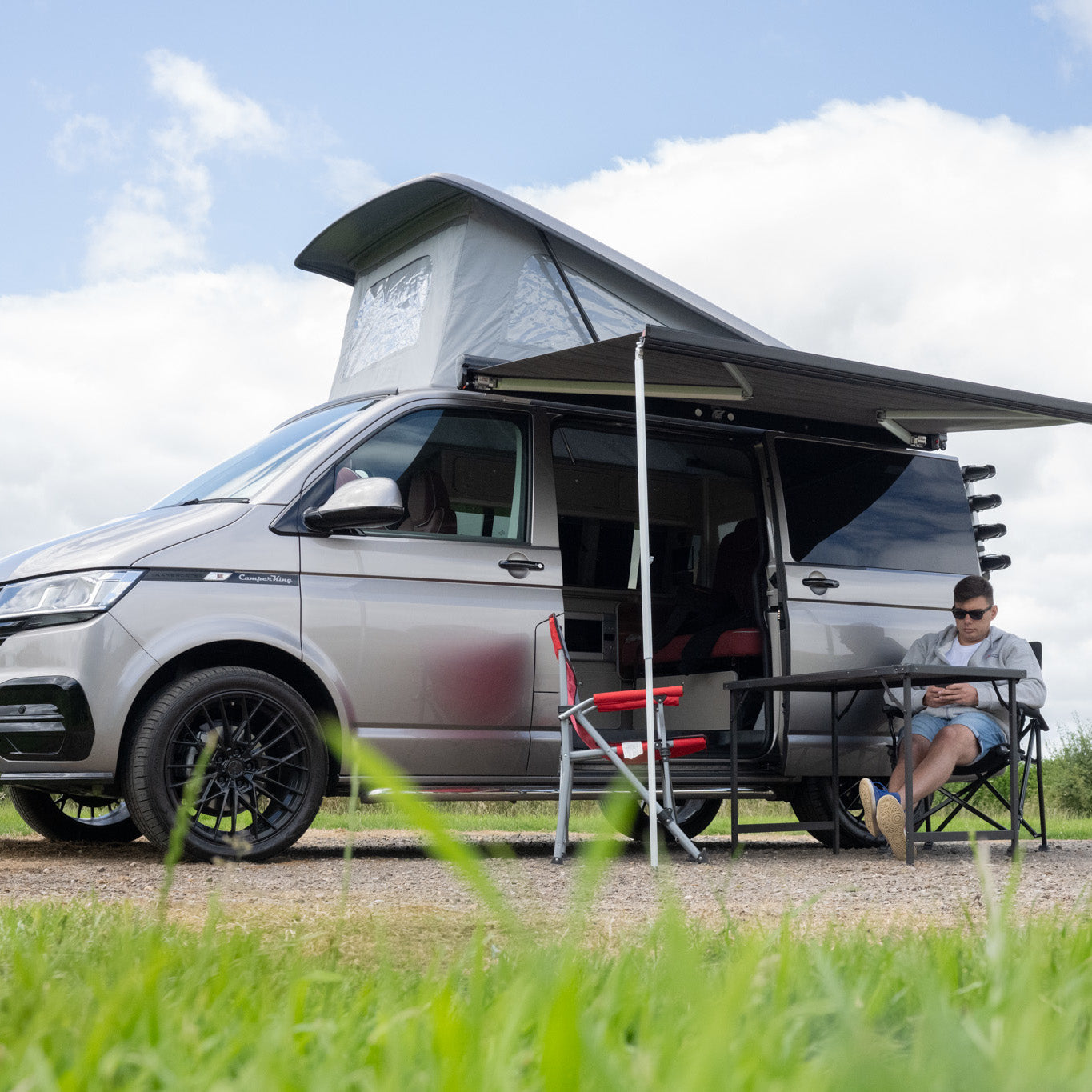 A happy couple taking a photo of themselves outside their well protected campervan.