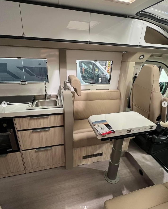 The inside of a campervan, showing the kitchen, seating and a folding table.