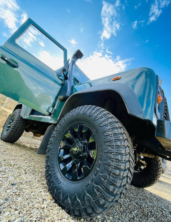A green off-road vehicle with large alloy wheels, photographed from low down.
