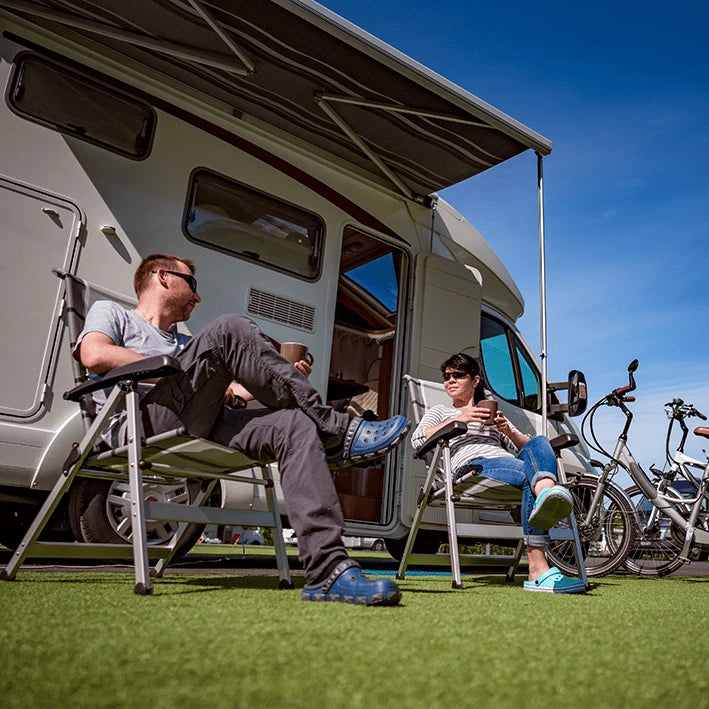 A happy couple taking a photo of themselves outside their well protected motorhome.