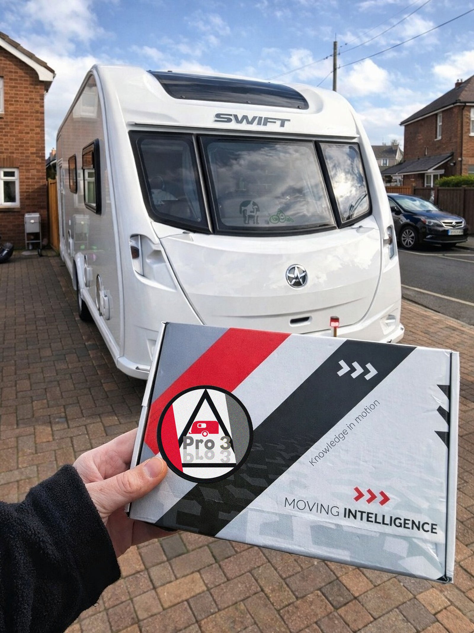 White caravan parked on a residential street with a hand holding a 'Pro 3' product box.