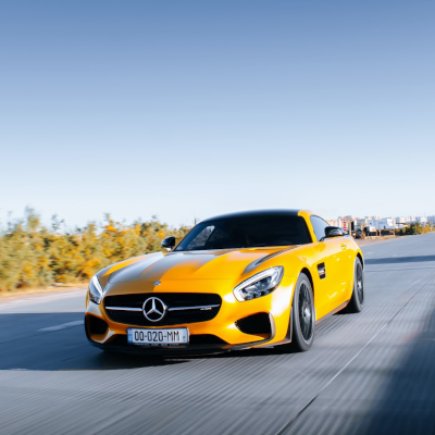 A yellow Mercedes-Benz sports car driving down a motorway protected by a state of the art GPS tracking device.