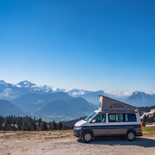 A happy couple taking a photo of themselves outside their well protected motorhome.