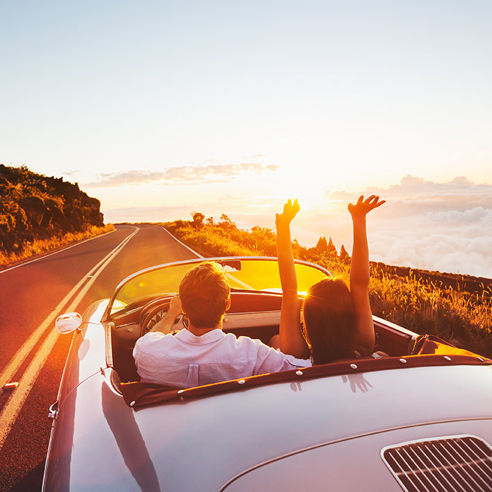 A happy couple driving at sunset in their expensive Mercedes-Benz convertible protected by a state of the art GPS tracking device.