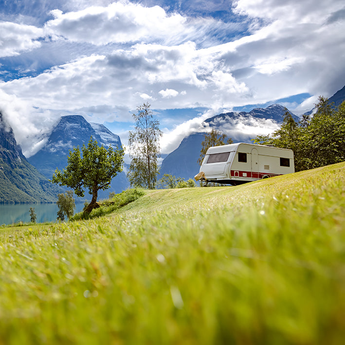 A caravan in the middle of a sunny field protected by Moving Intelligence highly rated service and tracking devices.