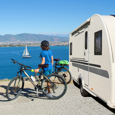 A woman looking at the sea besides her safe and secure caravan.